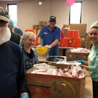 Volunteers smile for a photo while packing food together.